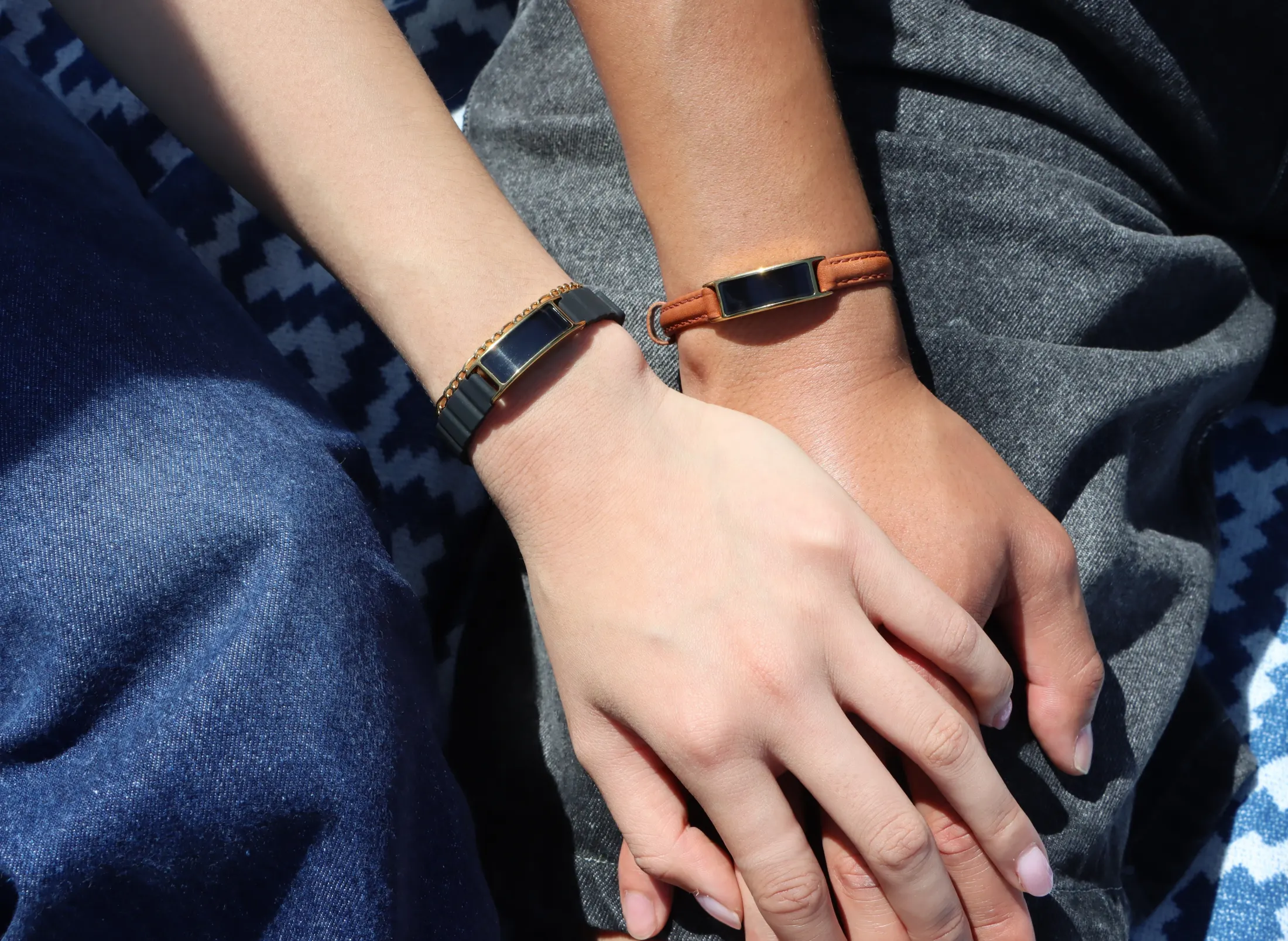 Two people holding hands, one wearing Ray on a leather band