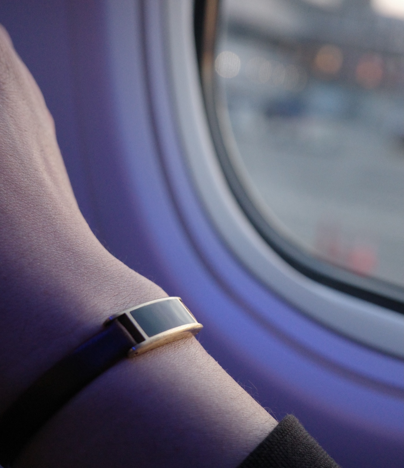 Gold Ray on a wrist beside an airplane window