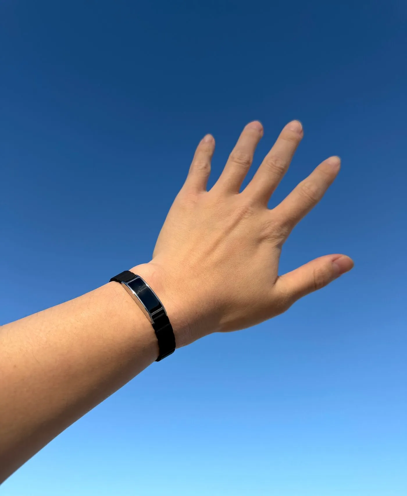 Ray worn on a wrist held up to a bright open sky