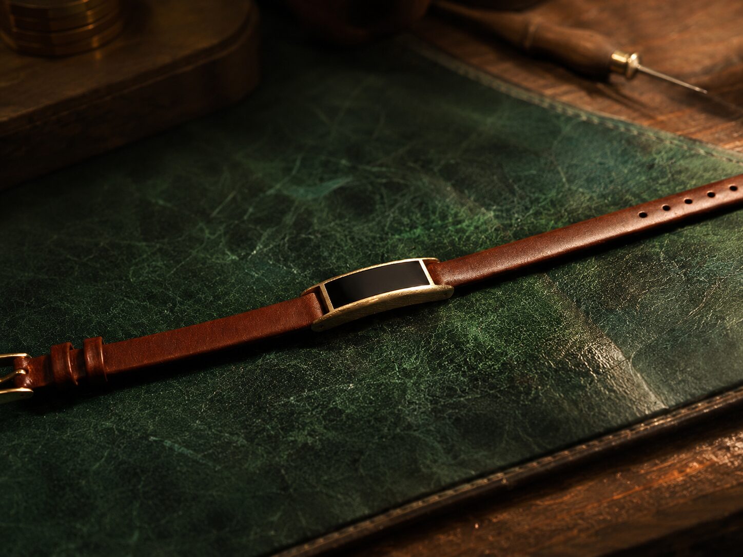 Ray in Sunlit Gold and Cognac Leather resting on the workshop's green leather desk mat