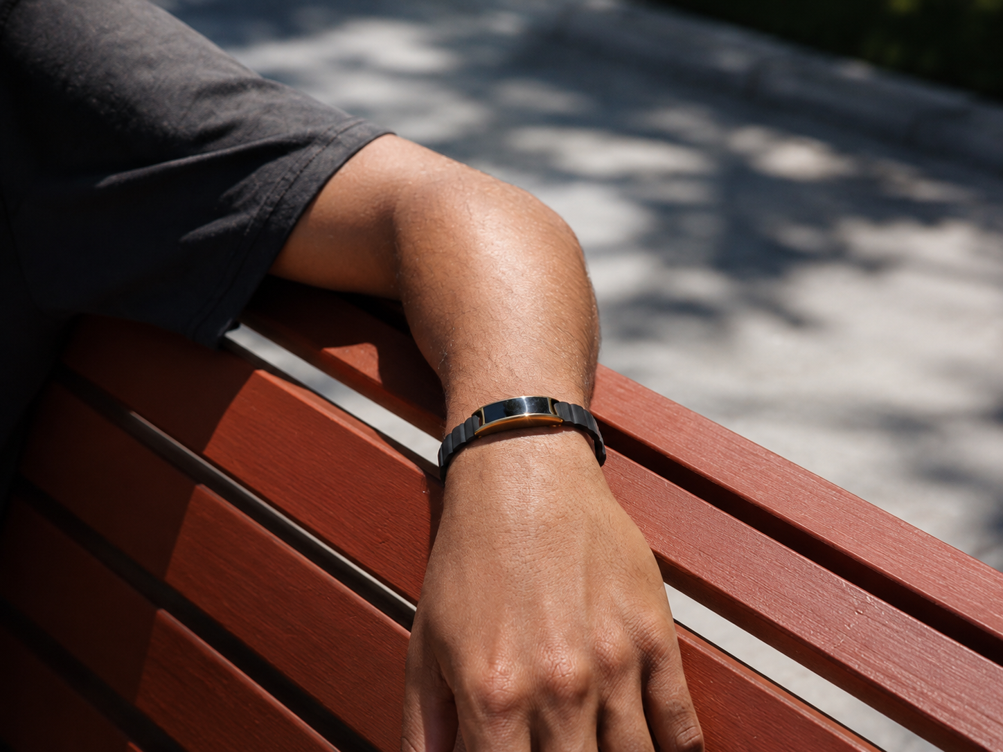 Ray in Sunlit Gold worn on an Onyx Leather band, resting over a park bench