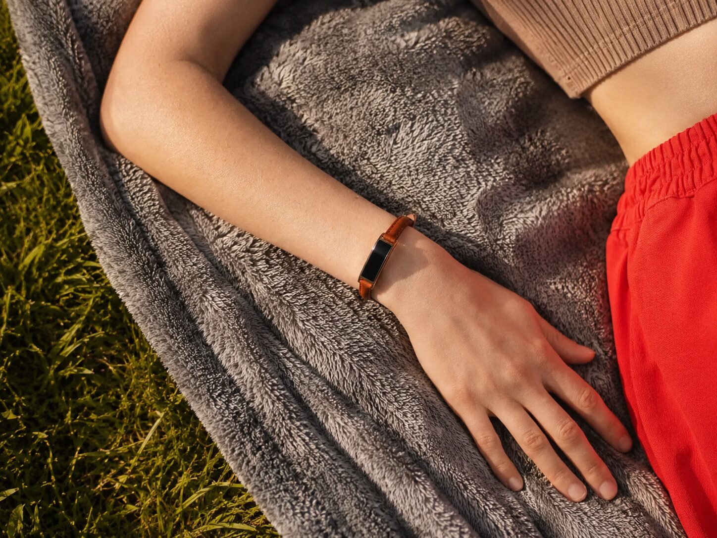 Ray worn on a cognac leather band, resting on a sunlit blanket outdoors